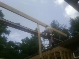 Carpenter setting a ridge beam over a new addition frame — Ice Dam Removal by Roofing Brothers in Latimer