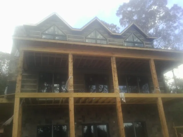 Dormers and porch framing on a large log home under construction — Roof Coating work by our crew in Latimer