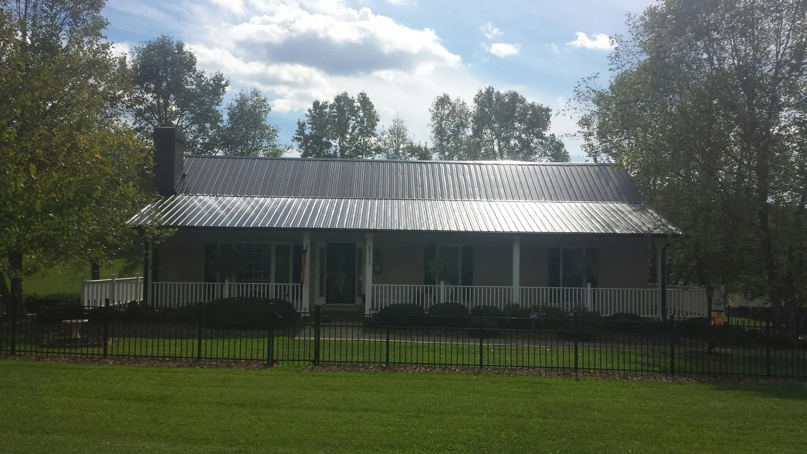 Gray metal roof on a brick ranch with a full width front porch — Gutter Guard Installation work by our crew in Latimer