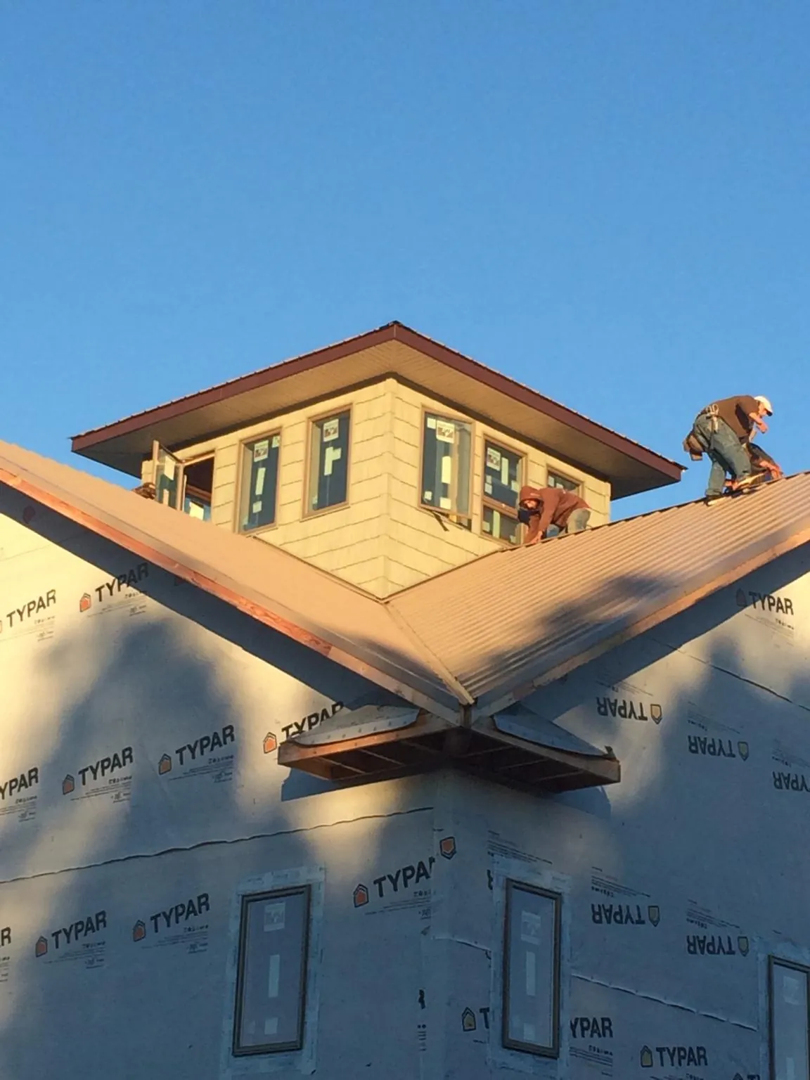 Roofers working around a rooftop cupola on a new metal roof at sunset — Roof Waterproofing in Latimer by Roofing Brothers